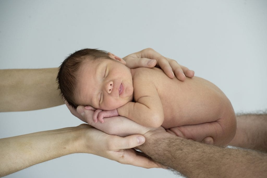 Baby Quade being held in the hands of mum and dad