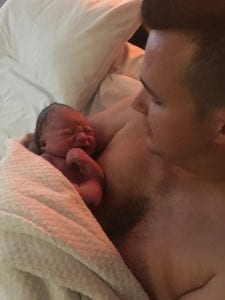 Dad Carl having skin to skin holding his baby boy