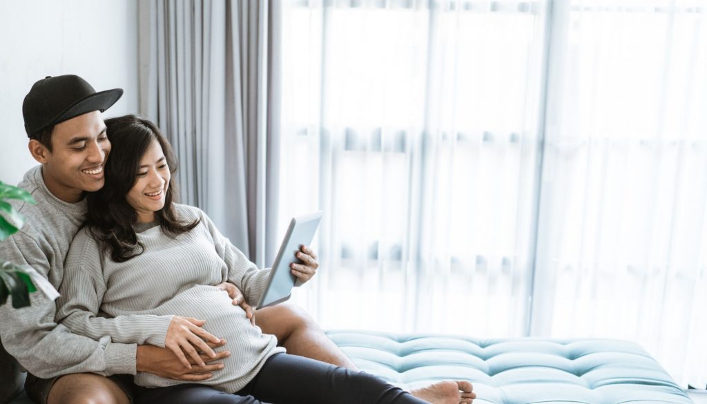 Husband and wife use tabs to view pregnancy