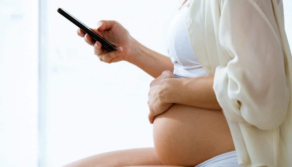 Close up of pregnant woman texting with her smartphone