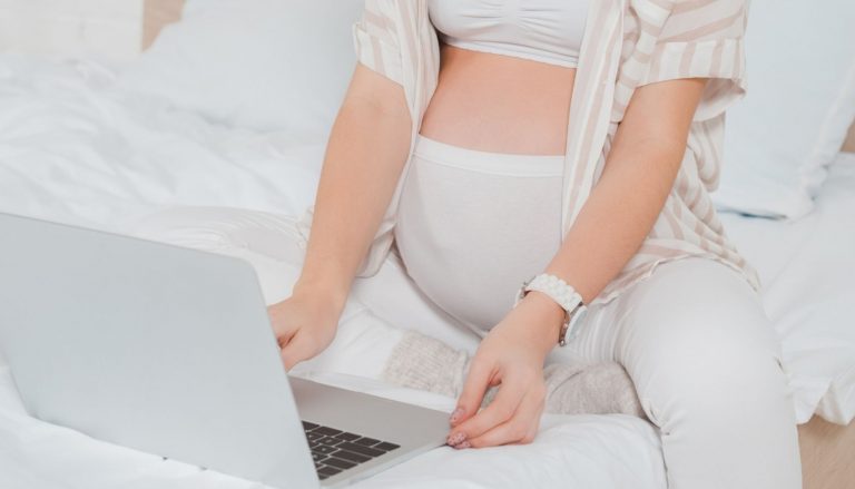 beautiful pregnant women using laptop on bed