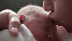 Mother kissing newborn on the forehead